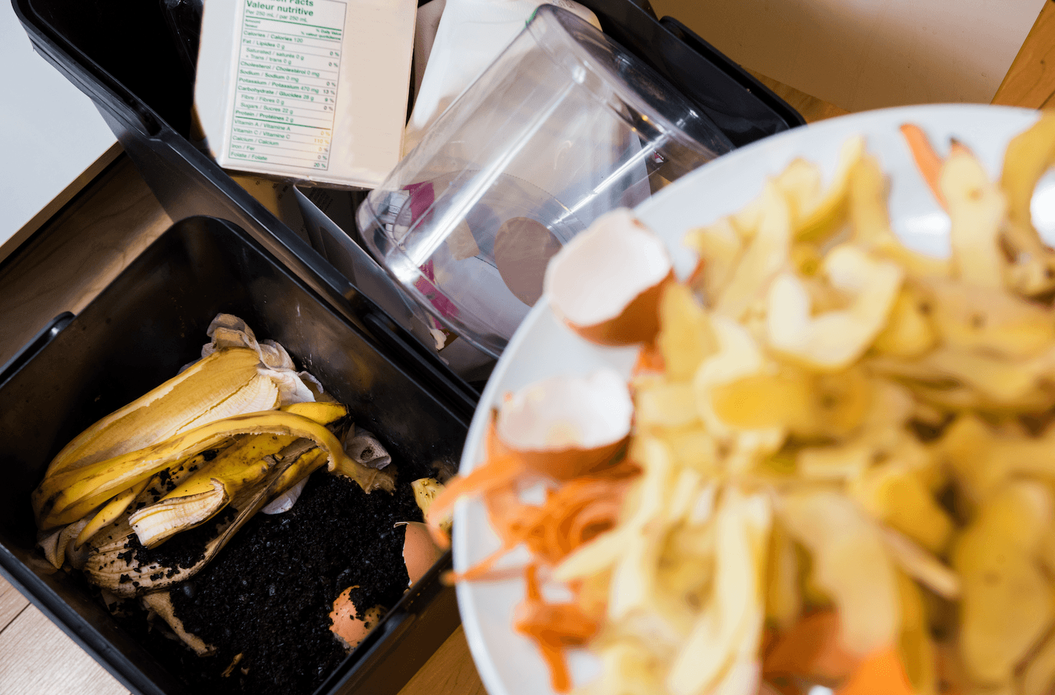 Kitchen composting setup with food scraps like potato peels, carrot peels, eggshells, and coffee grounds in bins, supporting sustainable waste practices and organics recycling.