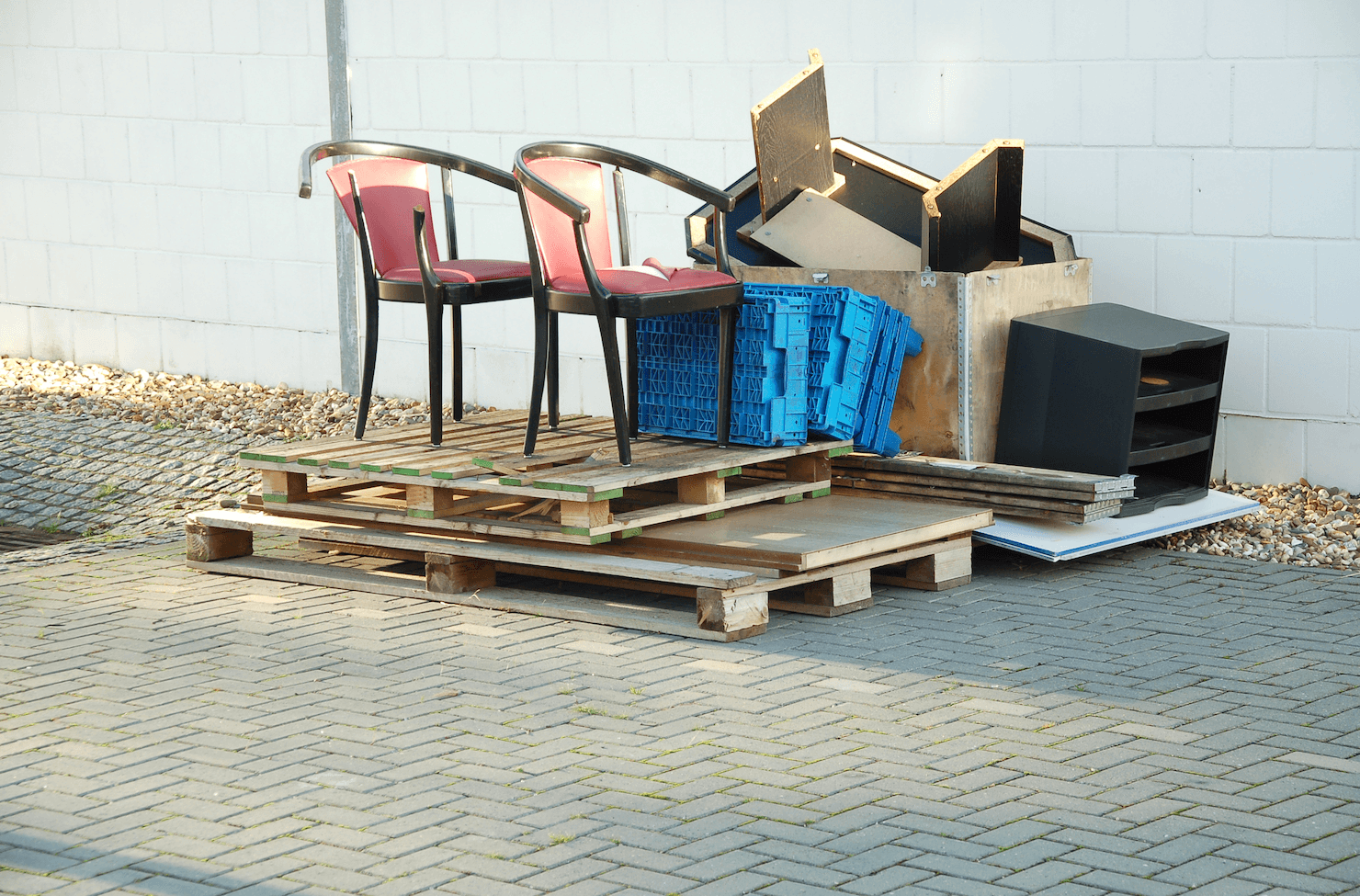 Stack of wooden pallets with discarded bulk waste such as furniture, plastic crates, and other items awaiting disposal.
